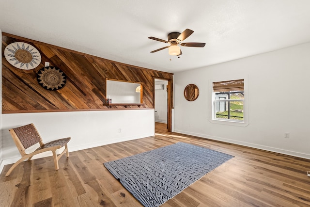 unfurnished room with ceiling fan, wooden walls, and light hardwood / wood-style floors