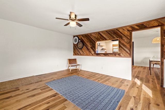 interior space featuring ceiling fan, wood walls, and light hardwood / wood-style flooring