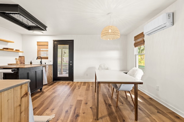 dining space featuring an AC wall unit, sink, and hardwood / wood-style flooring