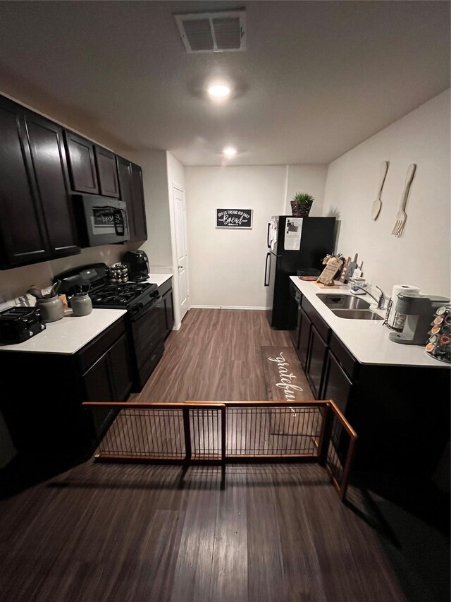 kitchen with sink, refrigerator, black gas stove, and wood-type flooring