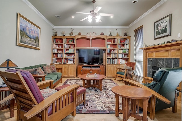 living room with ceiling fan, a fireplace, light wood-type flooring, and ornamental molding