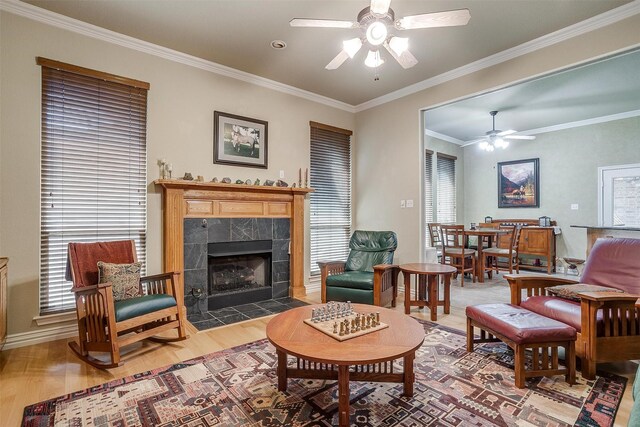 living room featuring ceiling fan, a fireplace, ornamental molding, and hardwood / wood-style floors