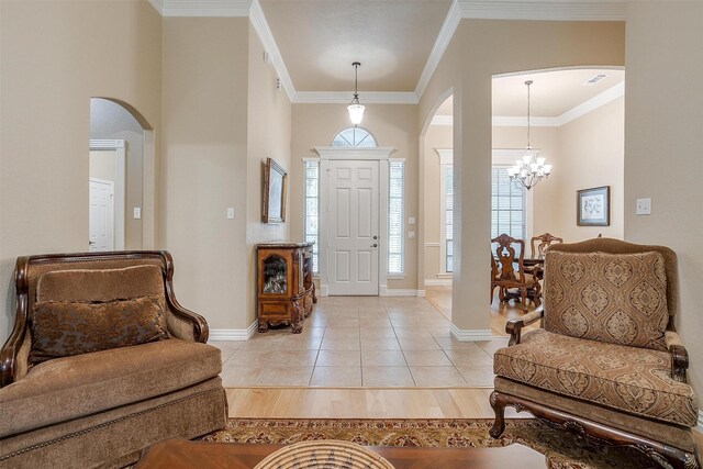 tiled entrance foyer featuring crown molding and a chandelier