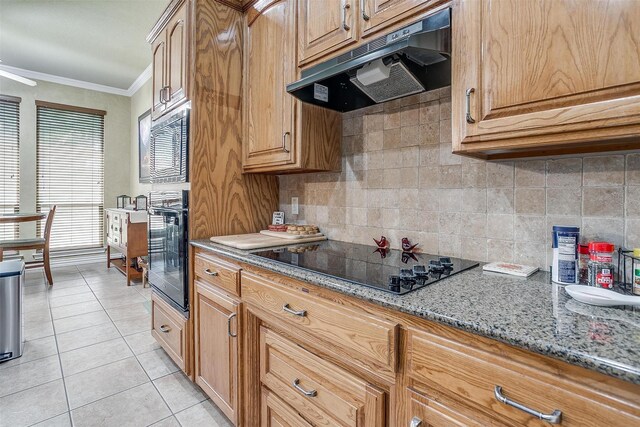 kitchen featuring light tile patterned floors, stone countertops, backsplash, ornamental molding, and black appliances