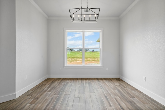 unfurnished room with hardwood / wood-style floors, crown molding, and an inviting chandelier