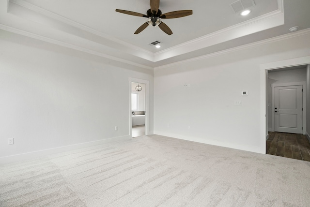 carpeted spare room featuring crown molding, ceiling fan, and a raised ceiling