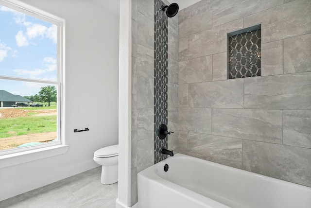 bathroom with toilet and tiled shower / bath