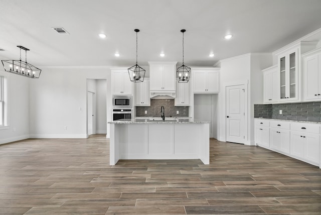 kitchen featuring white cabinetry, appliances with stainless steel finishes, pendant lighting, and an island with sink