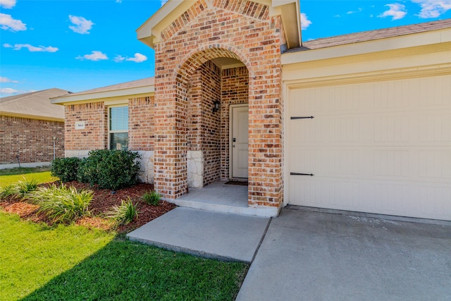 entrance to property featuring a lawn and a garage