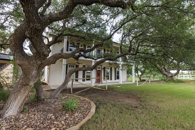 rear view of property featuring a patio area, a yard, and a balcony