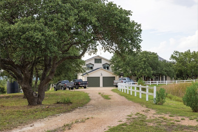 view of property hidden behind natural elements featuring a front lawn, an outdoor structure, and a garage