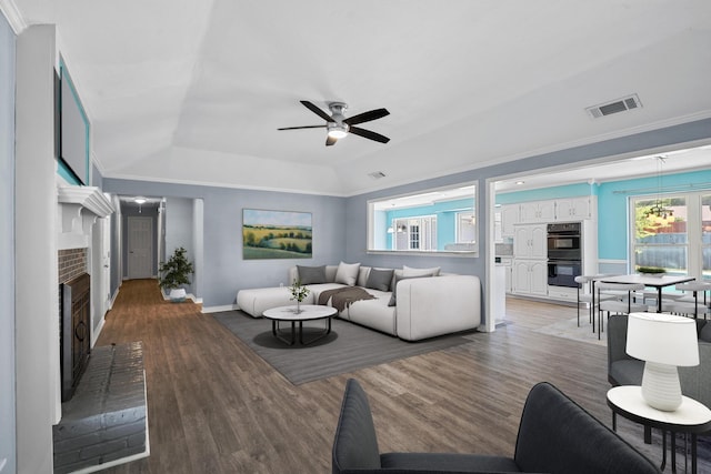 living room with ceiling fan, a fireplace, light hardwood / wood-style flooring, and ornamental molding