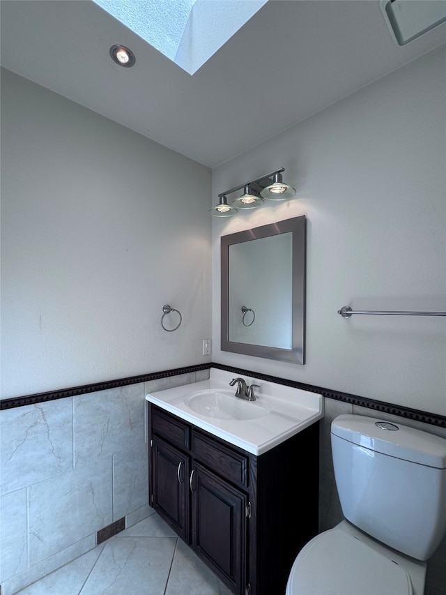 bathroom featuring tile patterned floors, a skylight, vanity, and toilet