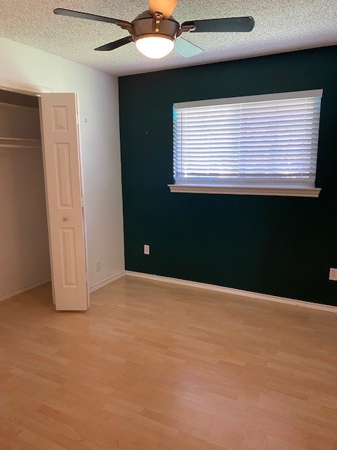 unfurnished bedroom featuring ceiling fan, light hardwood / wood-style floors, and a textured ceiling