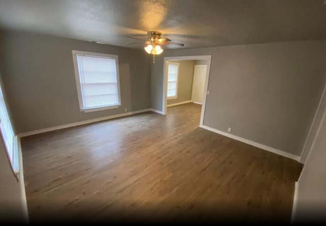 spare room featuring ceiling fan, wood-type flooring, a textured ceiling, and a healthy amount of sunlight