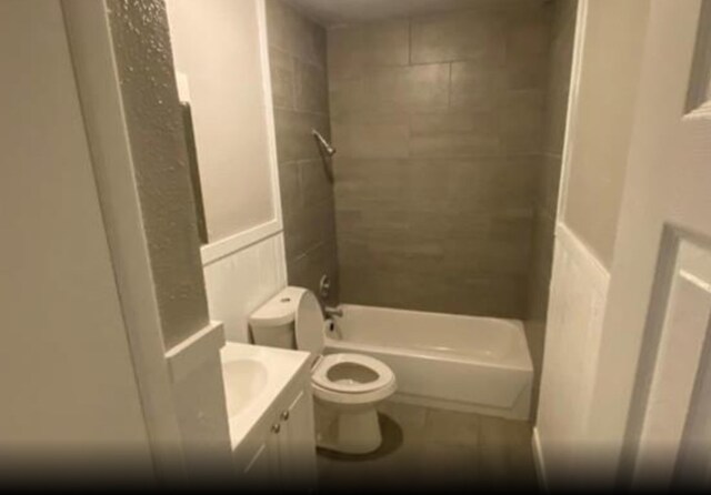 full bathroom with tile patterned flooring, toilet, tiled shower / bath, and vanity