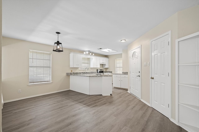 kitchen featuring kitchen peninsula, light hardwood / wood-style floors, white cabinets, and stainless steel stove