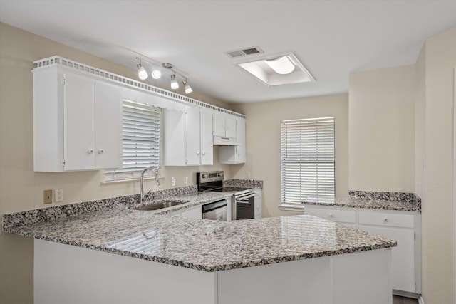 kitchen featuring sink, range, light stone counters, kitchen peninsula, and white cabinets