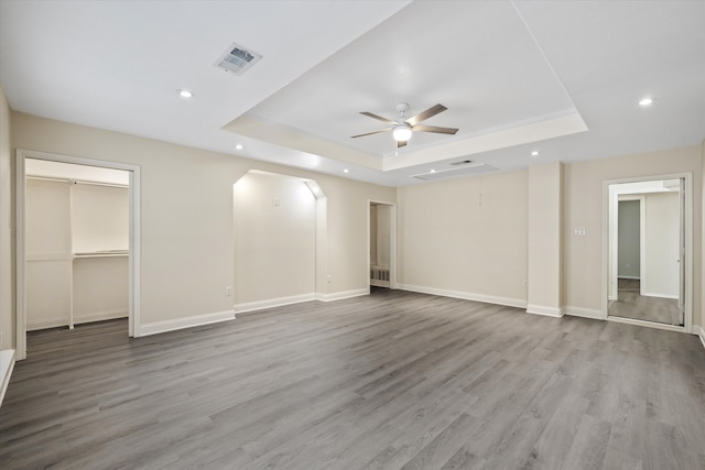 unfurnished bedroom with ceiling fan, hardwood / wood-style floors, and a raised ceiling