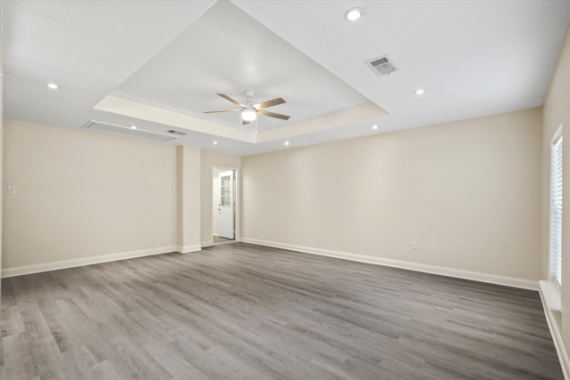 unfurnished room with ceiling fan, a raised ceiling, and wood-type flooring