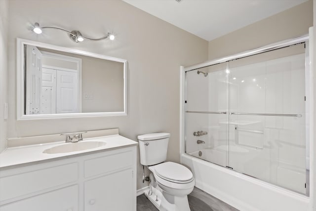 full bathroom with bath / shower combo with glass door, toilet, and vanity