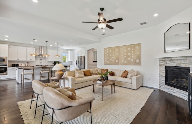 living room featuring sink, wood-type flooring, ceiling fan, and a fireplace