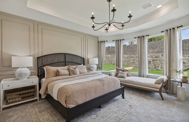 bedroom with light carpet, a tray ceiling, multiple windows, and a notable chandelier