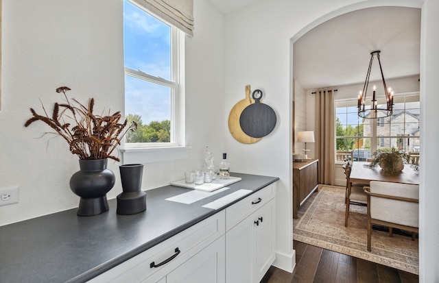 kitchen featuring white cabinetry, dark wood-type flooring, pendant lighting, and a notable chandelier