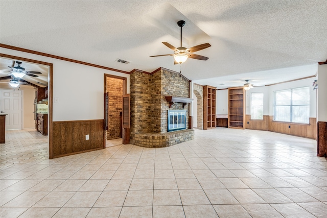 unfurnished living room featuring a fireplace, brick wall, ceiling fan, and light tile patterned floors