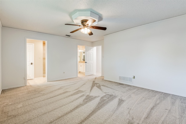 unfurnished bedroom with a textured ceiling, ceiling fan, connected bathroom, and light colored carpet