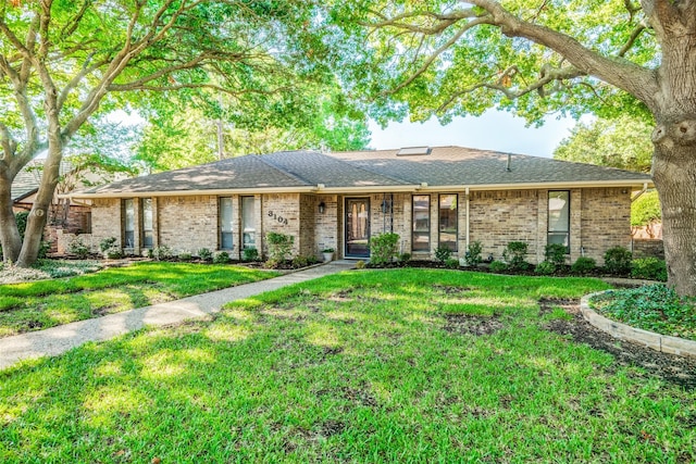 ranch-style house featuring a shingled roof, brick siding, and a front lawn