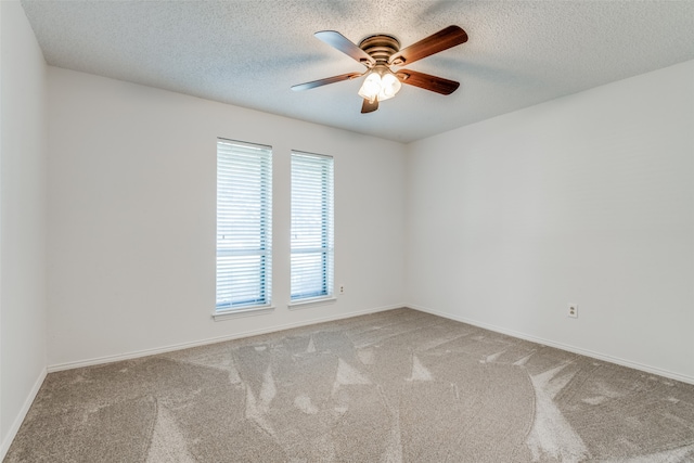 carpeted spare room featuring a textured ceiling, ceiling fan, and a healthy amount of sunlight