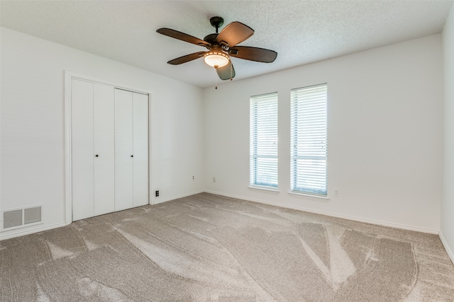 unfurnished bedroom featuring a textured ceiling, ceiling fan, and light colored carpet