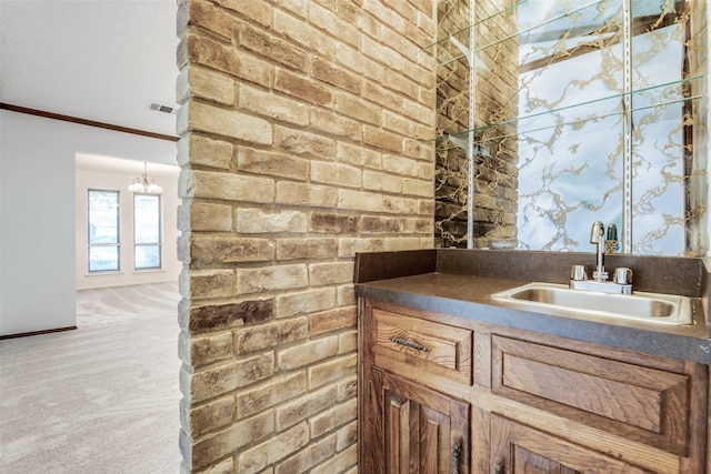 bathroom with crown molding, vanity, and brick wall