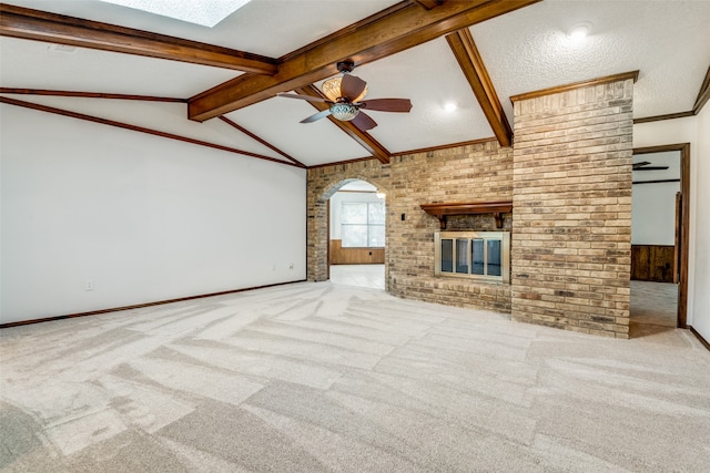 unfurnished living room featuring brick wall, ceiling fan, vaulted ceiling with beams, and a brick fireplace