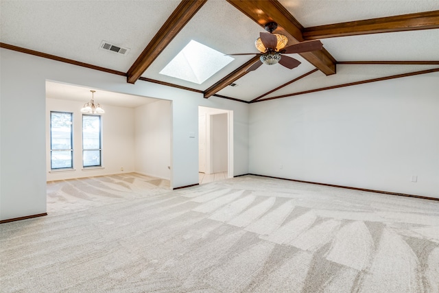 empty room featuring light colored carpet, a textured ceiling, ceiling fan with notable chandelier, and vaulted ceiling with skylight