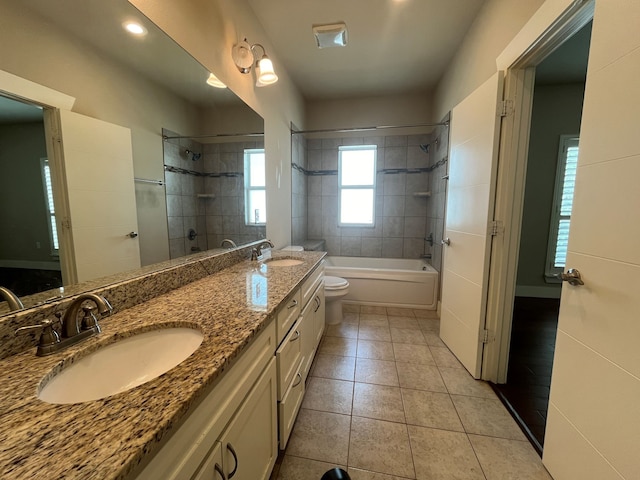 full bathroom with tiled shower / bath, toilet, dual bowl vanity, and tile patterned floors