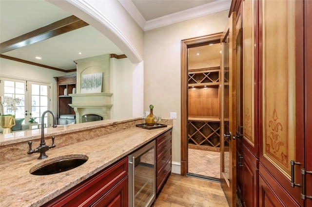 interior space with light hardwood / wood-style flooring, ornamental molding, light stone counters, wine cooler, and sink