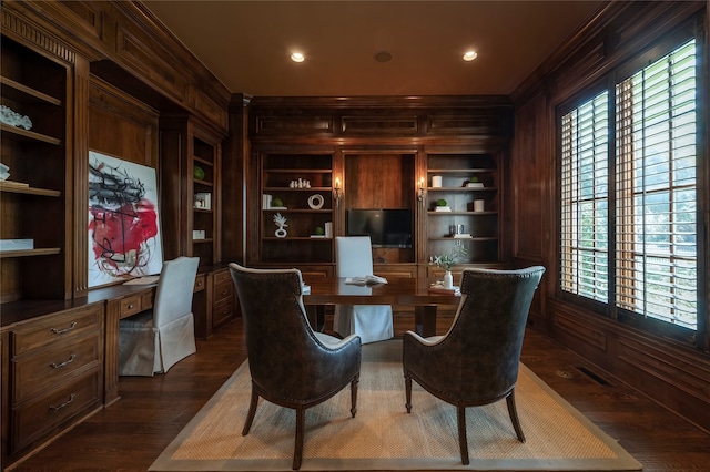 home office with built in features, dark hardwood / wood-style flooring, crown molding, and wooden walls