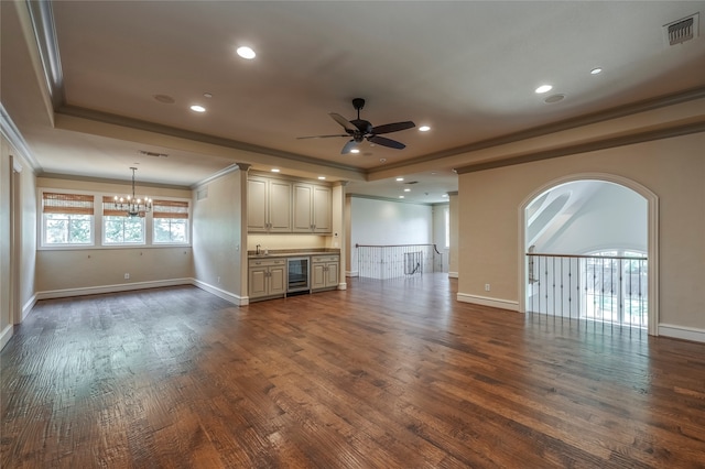 unfurnished living room with ornamental molding, a raised ceiling, ceiling fan with notable chandelier, wood-type flooring, and beverage cooler