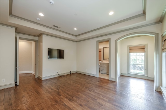 unfurnished living room featuring a raised ceiling, ornamental molding, and wood-type flooring