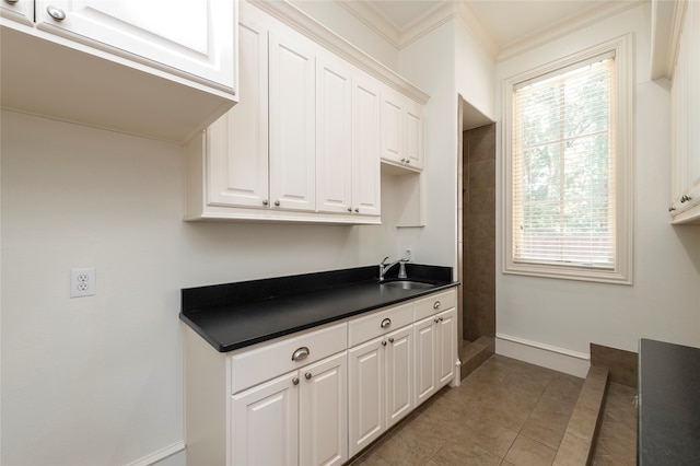 kitchen featuring light tile patterned floors, a wealth of natural light, sink, and white cabinetry