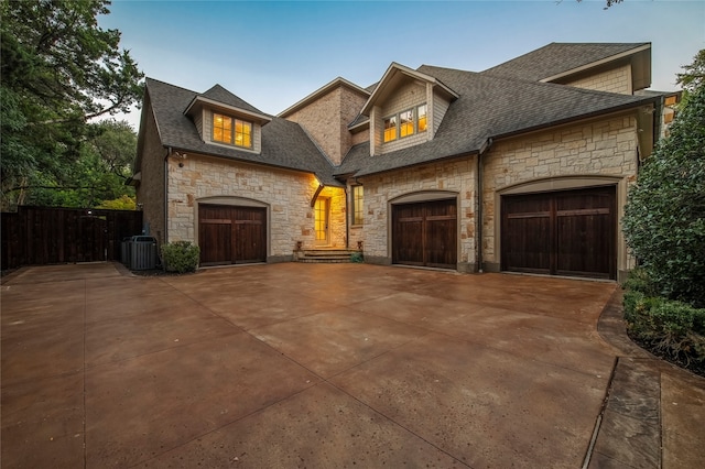 french provincial home featuring a garage and cooling unit