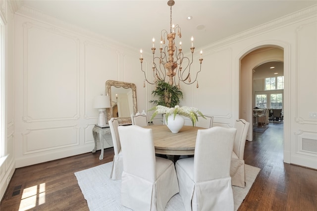 dining area with dark hardwood / wood-style floors, an inviting chandelier, and ornamental molding