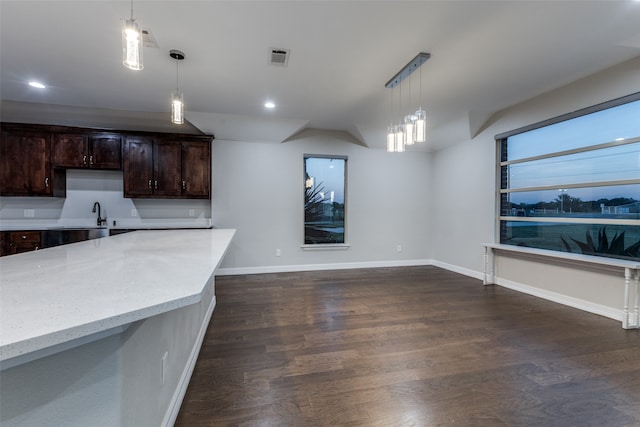 kitchen with dark hardwood / wood-style flooring, hanging light fixtures, light stone counters, and dark brown cabinets