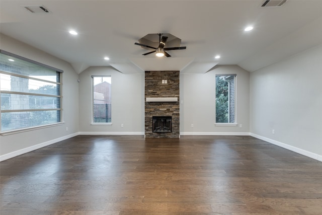 unfurnished living room with dark hardwood / wood-style flooring, lofted ceiling, a stone fireplace, and ceiling fan