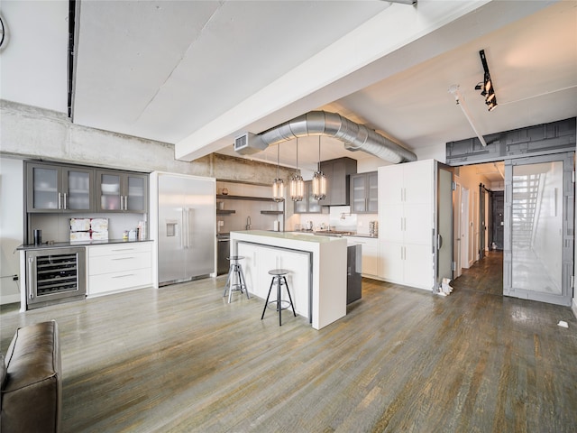 kitchen with pendant lighting, hardwood / wood-style floors, wine cooler, a breakfast bar area, and beamed ceiling