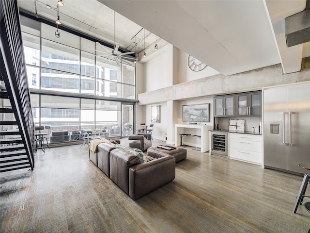 interior space with a high ceiling, wine cooler, wood-type flooring, track lighting, and a healthy amount of sunlight