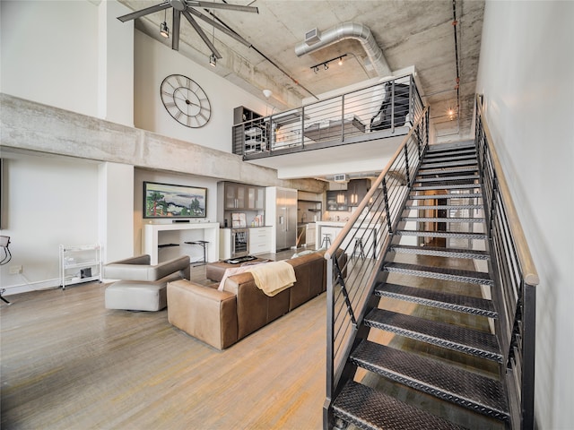 stairs with hardwood / wood-style floors, a towering ceiling, and ceiling fan