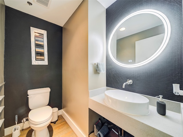 bathroom with toilet, vanity, and wood-type flooring